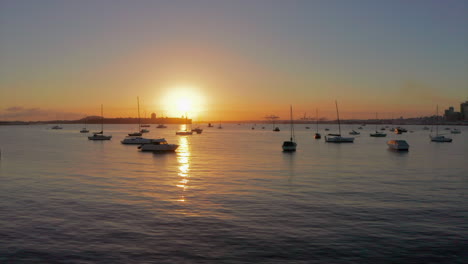 Sonnenuntergang-Beleuchtende-Boote,-Die-In-Der-Abenddämmerung-Im-Yachthafen-Vor-Anker-Liegen