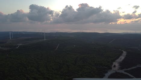 Wide-aerial-view-of-a-wind-farm-as-the-blades-of-a-wind-turbine-spin-in-the-foreground