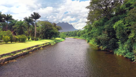Brazilian-river-in-tropical-green-forest-going-up-revealing-mountains-in-background