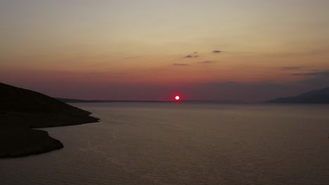 Left-tracking-shot-of-dramatic-sunset-over-calm-Croatian-sea,-aerial
