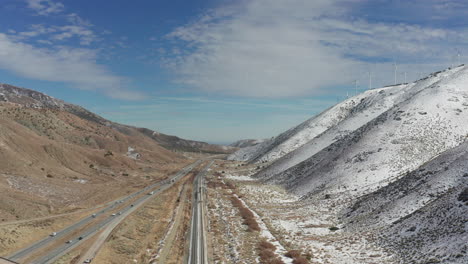Aerial-lowering-shot,-California-highway-by-snowy-mountains-on-winter-day