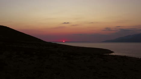 Colorful-orange-sunset-over-peaceful-Croatian-sea,-ascending-aerial