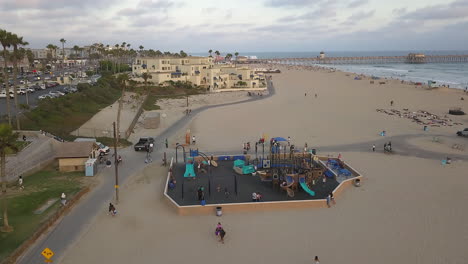Aerial-footage-of-people-and-kids-on-a-bike-path-and-beach-side-playground,-in-Huntington-Beach-California