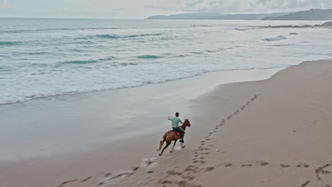 Aerial-Drone-Shot-of-Single-Man-Horseback-Riding-Galloping-along-the-Beach-in-Tambor,-Costa-Rica