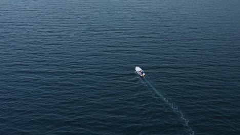 Ein-Einzelnes-Kleines-Weißes-Motorboot,-Das-Eine-Weite-Meeresfläche-überquert,-Aus-Der-Luft
