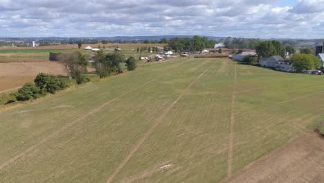 Aerial-View-of-Farm-Countryside-with-a-Antique-Steam-Train-Approaching-Through-it-on-a-Sunny-Partly-Cloudy-Day-as-Seen-by-a-Drone