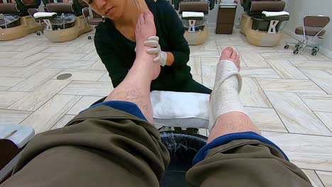POV,-Female-pedicurist-using-hot-tower-on-man's-feet-and-leg-at-the-end-of-a-pedicure