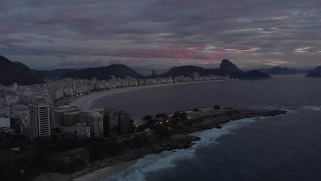 Early-morning-aerial-sideways-pan-showing-sunrise-over-Copacabana-beach-with-the-Copacabana-fort-in-the-foreground-and-the-Sugarloaf-mountain-in-the-background
