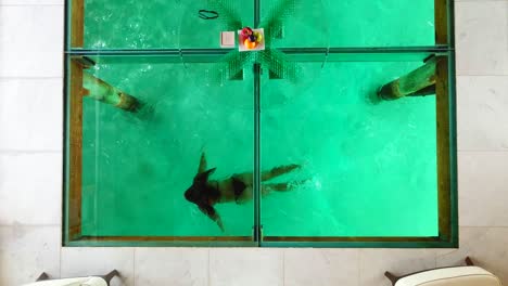 Top-view-of-a-window-floor,-woman-swimming-under-a-villa,-on-the-Conrad-Rangali-islands,-in-Maldives