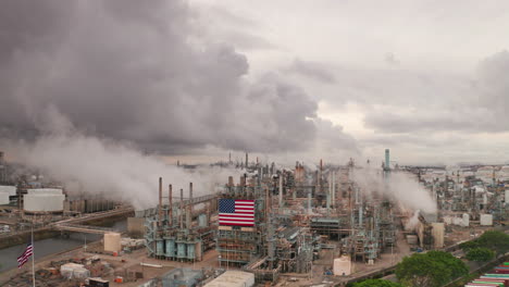 Dampf-Strömt-Aus-Schornsteinen-In-Der-Amerikanischen-Fabrik-Mit-US-Flagge-Und-Grauen-Wolken