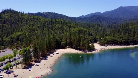 A-Beautiful-Whiskeytown-Lake-In-California-Surrounded-With-Tall-Pine-Trees-And-White-Sand---Aerial-Shot