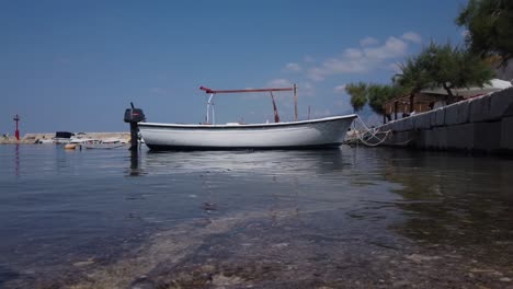 Blick-Auf-Den-Wasserspiegel-Eines-Kleinen-Fischerbootes,-Das-In-Einem-Ruhigen-Kroatischen-Yachthafen-Festgebunden-Ist