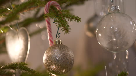 Transparent-Christmas-Baubles-hanging-in-real-Christmas-tree,-Close-up-Pan-left