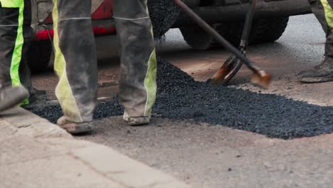 Construction-workers-are-spreading-new-asphalt-onto-broken-patch-of-road