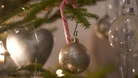 Traditional-Swedish-Polkagris-candy-decoration-placed-on-real-Christmas-fir-tree,-sliding-close-up
