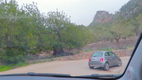 A-drive-in-Sant-Llorenç-zigzag-road-showing-traditional-Mallorcan-village-greenery,-following-a-car-Mallorca,-Spain,-captured-from-car-windscreen