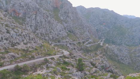 A-huge-long-view-of-a-zigzag-road-with-mountains-series-with-lush-forest-in-winters-at-Mallorca,-Spain