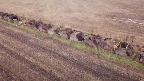 Fly-over-harvested-fields-with-abandoned-small-farrowing-hog-crates-along-the-fence-line