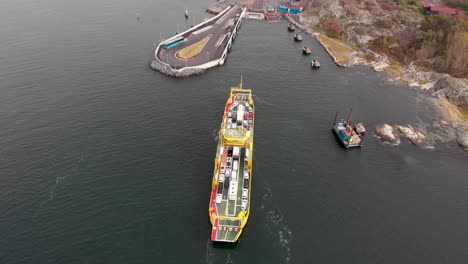 Aerial-drone-flight-over-yellow-loaded-car-ferry-approaching-the-dock-in-northern-Gothenburg,-Sweden