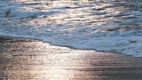 Slow-motion-of-sea-water-waves-splashing-against-golden-sand-beach