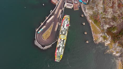 Top-down-aerial-drone-view-of-car-ferry-that-is-about-to-dock-in-Gothenburg's-northern-archipelago,-Sweden