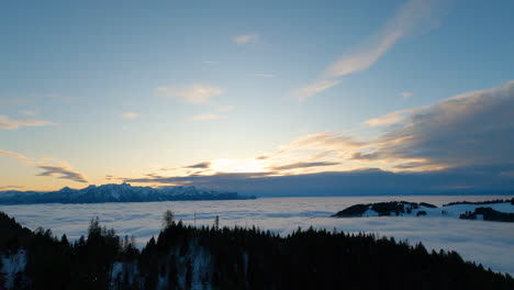 Beautiful-thick,-white-fog-covering-the-Swiss-Plateau-area-at-dusk-with-the-Alps-in-background-in-winter---Aerial-shot,-Switzerland