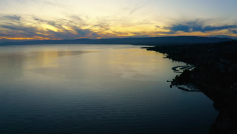 Beautiful-blue-and-yellow-sunset-view-over-the-shores-of-Lake-Leman-Lutry-in-Switzerland---Aerial-shot