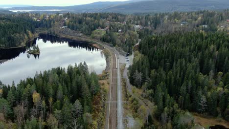 Aerial-view-of-train-tracks-and-lake-in-mountains-with-trees