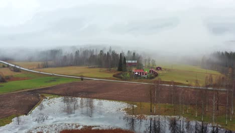 Aerial-shot-of-a-farm-next-to-a-road-and-lake-in-the-middle-of-Sweden