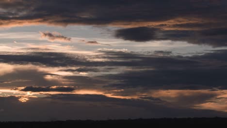Dramatische-Wolken-Während-Des-Orangefarbenen-Sonnenuntergangs-Mit-Der-Silhouette-Eines-Baumes-Davor