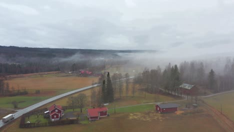 Aerial-shot-of-a-farm-in-Sweden-covered-in-clouds