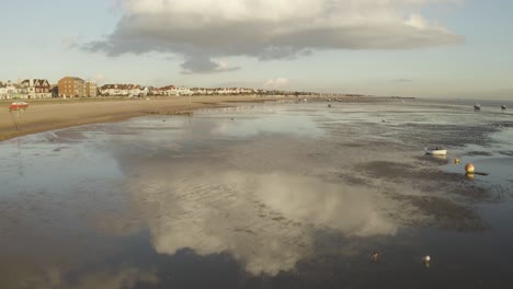 Reflections-of-clouds-on-the-ocean-waters-along-the-beach-at-low-tide-in-the-UK,-Southend