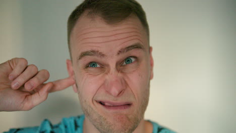 Close-up-of-young-man-putting-a-finger-in-his-ear