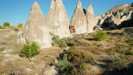 Woman-on-quad-bike-travels-on-trail-through-Cappadocia-landscape-past-fairy-chimney-rocks
