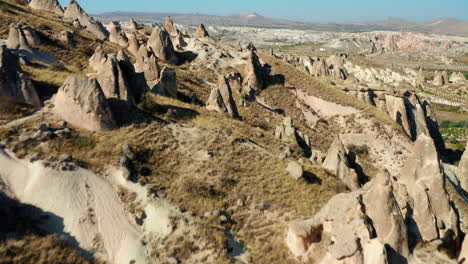 Flying-over-jagged-rocky-landscape-of-Goreme,-unique-Cappadocia-formations-in-Turkey