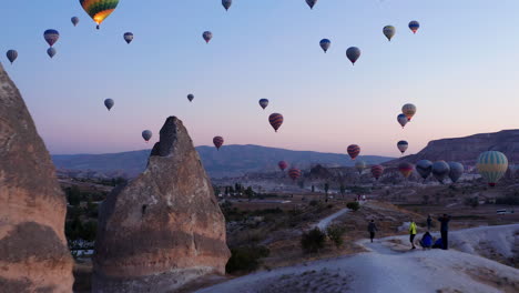 Hot-air-balloons-fill-the-morning-sky-at-Goreme,-forward-push-over-breathtaking-landscape-of-Cappadocia