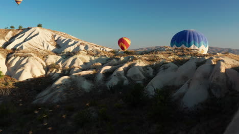 Fliegen-Durch-Die-Landschaft-Der-Türkei,-Während-Ein-Vogelschwarm-Mit-Einem-Heißluftballon-Im-Hintergrund-Vorbeizieht