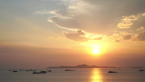 Atemberaubender-Tropischer-Sonnenuntergang-Hinter-Einer-Fernen-Insel-Und-Boote,-Die-Im-Ruhigen-Ozean-Verankert-Sind