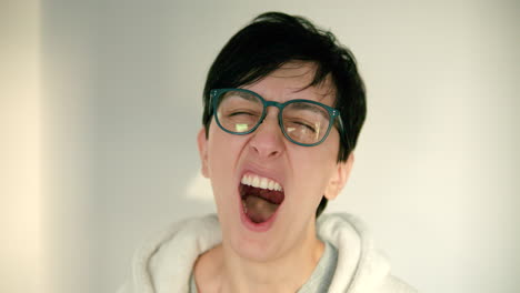 Close-up-of-young-woman-with-glasses-and-short-hair-yawning-in-slow-motion