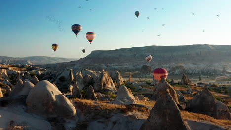 Vogelschwarm-Fliegt-über-Die-Landschaft-Der-Türkei-Mit-Heißluftballons-Schweben-Im-Hintergrund