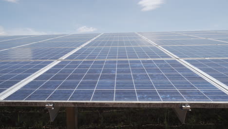 Dolly-De-4k-Entra-Y-Sale-De-Un-Conjunto-De-Paneles-Fotovoltaicos-Solares-Dentro-De-Una-Gran-Planta-De-Energía-Solar-Con-Muchos-Módulos-Policristalinos-Fotovoltaicos-Con-Un-Cielo-Azul-Claro