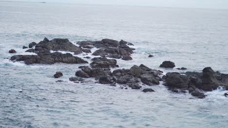 Entspannende-Blaue-Wellen,-Die-In-Felsformationen-Auf-Meer-Stürzen