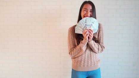 Excited-Asian-woman-celebrating-winning-lots-of-money-online-in-the-lottery