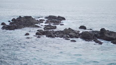 Beruhigende-Blaue-Wellen,-Die-In-Felsformationen-Auf-Meer-Stürzen