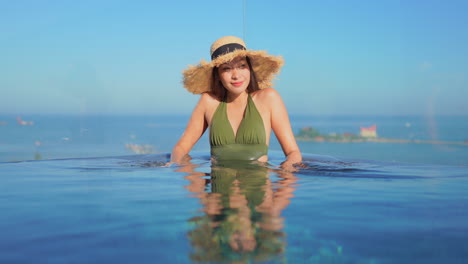 Junge-Hübsche-Asiatische-Frau,-Die-Sich-Am-Rand-Eines-Resort-infinity-pools-Entspannt,-Ist-Im-Poolwasser-Spiegelbildlich-Dargestellt