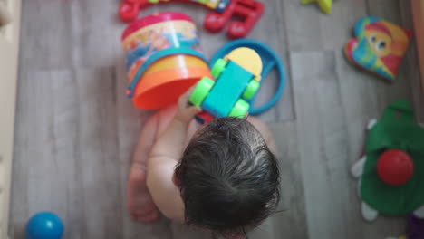 Slow-Motion-high-angle-shot-of-an-adorable-one-year-old-asian-boy-playing-by-himself-with-a-colorful-toy-train-inside-a-beach-bucket-at-home