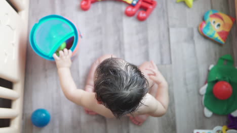 Slow-Motion-high-angle-shot-of-a-cute-one-year-old-asian-baby-playing-by-himself-with-colorful-toys-inside-an-indoor-playground-on-the-floor-of-his-home