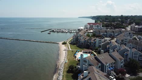 Cinematic-Aerial-of-Chesapeake-Bay-Beach-Properties,-Jetty-and-Boats-in-Marina-on-Sunny-Summer-Day