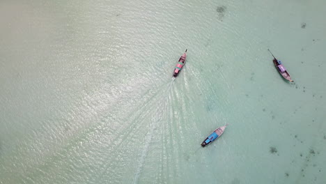 Top-Down-Drone-Aerial-View-on-Thaditional-Thai-Boat-Sailing-in-Shallow-Water-on-White-Sand-Beach-on-Koh-Phi-Phi-Don-Island,-Krabi