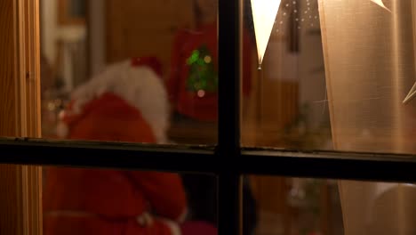 Santa-Claus-visit-on-Christmas-Eve-handing-out-X-mas-presents-to-children,shot-through-window